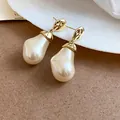 Close-up of French retro irregular pearl drop earrings with textured gold accents. - Gold Irregular Pearl Earrings / Gold