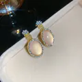 Détail de boucles d'oreilles dorées avec œil-de-chat rose ovale et halo cristallin - Boucles d'Oreilles Seules (HE32789-1) / Or-Rose