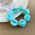 Primer plano detallado de una pulsera bohemia de cuentas de acrílico turquesa en concha. - Pulsera / Cian