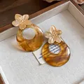 Detail of French vintage earrings featuring gold metal flowers and marbled amber resin hoops - Flower Round Stud Earrings (HE33078) / Brown