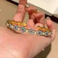 Exquisite gold-tone open bangle with blue oil-drop flowers and cat's eye stones - Bangle / Gold-Blue