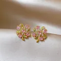 Detailed view of elegant pink and white zircon flower stud earrings on champagne satin - Flower Shape / Gold-Pink-Green