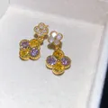 Primo piano di eleganti orecchini a fiore con scintillanti zirconi viola e gialli - Colorato
