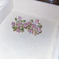 Dettaglio ravvicinato di orecchini a lobo a fiore con zirconi rosa e verdi lucenti - Rosa e Verde