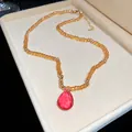 Detailed shot of amber beaded necklace with a pink faceted teardrop crystal pendant - Necklace (HN11875) / Brown and Pink