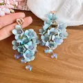 Detailansicht von eleganten blauen Stoffblumen-Ohrringen mit Herz-Kristallanhängern - Silbernadel-Blau
