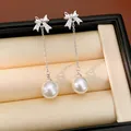 Détail de boucles d'oreilles nœud en argent avec zircons et perles blanches pendantes - Blanc