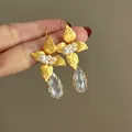 Primo piano di orecchini a fiore dorati con perle e gocce di cristallo sfaccettato - Ganci per orecchini / Oro