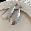 Gros plan de grandes boucles d'oreilles en argent avec un design froissé en forme de goutte - Plis / Argent