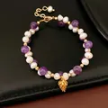 Macro view of 18k gold plated bracelet featuring white pearls and amethyst beads - Pine Cone Charm Style / Real Gold Plated / Purple-White