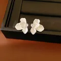 Detail shot of white enamel flower stud earrings with a tiny sparkling zircon center - White