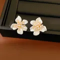Elegant white flower stud earrings with small pearls and sparkling zircons on gold-tone base - Gold-White