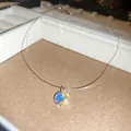 Vue détaillée du pendentif en cristal irisé sur un cordon invisible transparent. - Pendentif rond / Argent