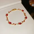 Detailed view of the gold-plated vine bracelet featuring ruby-red oval zircons. - Red Vine / Gold