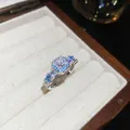 Close-up detail of a silver-finish ring with square zircon and blue stones in a jewelry box. - Open Ring / Silver-Blue
