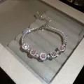 Gros plan d'un bracelet scintillant en zircon rose et diamants dans un écrin gris - Cinq Strass Carrés Roses (16#) / Rose (16#)