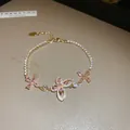 Gros plan d'un élégant bracelet papillon doré orné d'oxydes de zirconium roses et clairs - Papillon et Fleur Alternés (20#) / Or-Rose (20#)