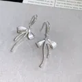 Close-up of elegant bowknot earrings with sparkling zircons and white enamel finish - Earring Hooks - Silver