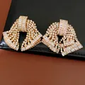 Primo piano dettagliato di orecchini vintage a fiocco con zirconi baguette scintillanti - Oro Bianco