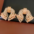 Primo piano di orecchini vintage a fiocco con zirconi rosa e strass brillanti e lucenti - Oro Champagne