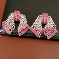 Primo piano di orecchini vintage a fiocco con zirconi rosa su pelle nera - Argento Rosa