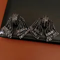 Dettaglio macro di orecchini a fiocco vintage con zirconi neri su sfondo in pelle - Canna di fucile