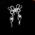 Primo piano di orecchini a clip a fiocco con zirconi e perle con finitura argento - Stile Fiocco Perla / Argento