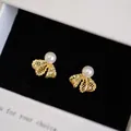 Close-up of gold-plated bow earrings with white pearl and zircon accents - Gold Bowknot Style (HE33196)