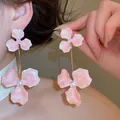 Close-up van bohemian roze bloem oorbellen met parels op het oor van een model - 34# Roze Driebladige Bloem Parel Lange Hanger Oorbellen