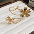 Detailed macro view of a golden flower arm cuff featuring intricate textured metal band - Gold
