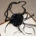 Primo piano di un'elegante collana di perle nere con fiori in pizzo e dettagli in piuma - Nero