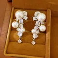 Close-up of elegant pearl and zircon cluster clip-on earrings in a wooden jewelry box - Silver