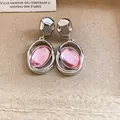 Macro view of silver-toned stud earrings featuring unique oval pink acrylic pendants - Oval Pendant (HE33150) / Pink