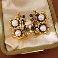 Detailed macro shot of vintage flower earrings with pearls and crystals in a velvet box - Gold