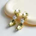 Nahaufnahme von goldenen, quadratischen Vintage-Ohrringen mit eleganten Perlenakzenten - Ohrringe / Gold-Weiß