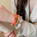 Primo piano di tre braccialetti elastici impilati in acrilico e tonalità oro su un polso. - 22# Braccialetto / Set di 3 / Oro, Arancione, Trasparente
