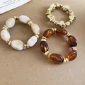 Close-up of three irregular acrylic elastic bracelets in gold, amber, and white marble. - 51# Bracelet / Three-Piece Set / Gold-Coffee-Khaki
