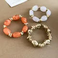Close-up of three irregular acrylic elastic bracelets in orange, white and gold - 48# Bracelet / Three-Piece Set / Gold-Orange-Transparent