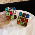 Detailed view of vintage square stud earrings with multi-colored gemstones on a pearl shell - Gold-Multicolor