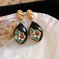 Detailed view of vintage black enamel drop earrings with floral patterns and crystals. - Black