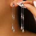 Elegant long silver tassel earrings with polished teardrop metal charms on a model - 05 White K Dz-003