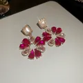 Gros plan de boucles d'oreilles de luxe en cristal fuchsia avec détails dorés et pierres blanches. - 26# Boucles d'Oreilles-Pierre Colorée Dorée