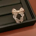 Detail of hollow-out bow ring with mesh texture on black leather display tray. - Hollow Bow Style / Light Coffee Gold