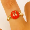 Close-up of a gold-toned bead ring with a red enamel initial K on a finger for women - English Letter K Ring (9805) / Red