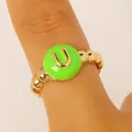 Macro view of golden beaded letter U ring featuring a vibrant green enamel center - English Letter U Ring (6446) / Green