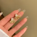 Detailed close-up showing the elegant 18K gold plated bow stud earrings with a white pearl - Gold