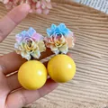 Detailed view of colorful resin flower earrings with large yellow spherical beads - Yellow