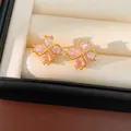 Primer plano de exquisitos aretes de trébol con circonitas rosas y chapado en oro de 18k - Rosa