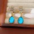 Detailed view of vintage flower stud earrings with sparkling crystals and blue teardrops - Silver Needle / Blue