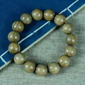 Poliertes braunes Sandelholz-Perlenarmband mit natürlicher Maserung auf dunkelblauem Buch - Einzelschleifen-Stil / 15mm x 15 Stk
